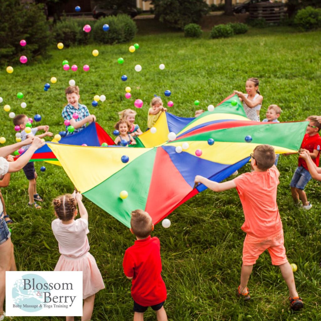 Rebuilding the Parent–Child Village: What Has Caused the Erosion of Our Communities? - a group of different aged children playing with a coloured sheet and balls outside in a field