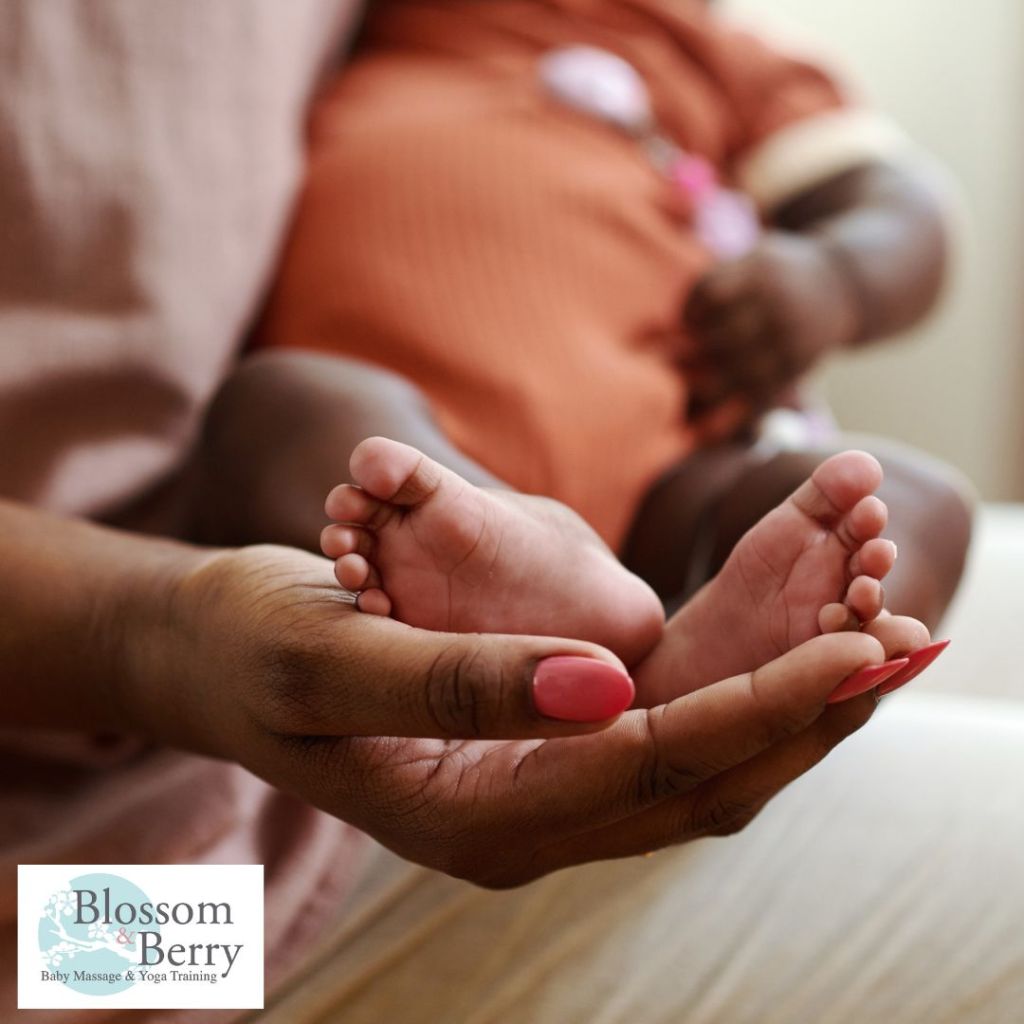 A parent gently cupping a baby's tiny feet in their hands during a peaceful moment of touch and bonding.